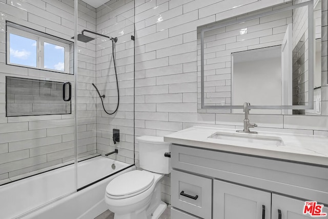 full bathroom with toilet, bath / shower combo with glass door, tile walls, and vanity