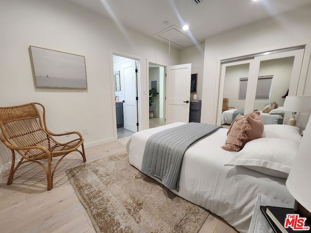 bedroom featuring connected bathroom and light hardwood / wood-style flooring