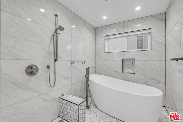 bathroom featuring tile walls, tile patterned floors, and a tub