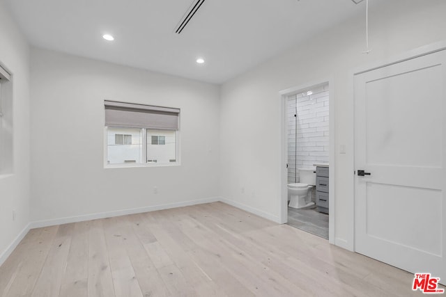 unfurnished bedroom featuring light hardwood / wood-style floors and connected bathroom