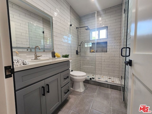 bathroom with tile patterned floors, walk in shower, vanity, and toilet