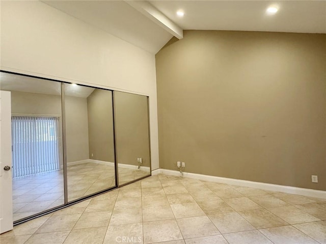 unfurnished bedroom featuring a closet, light tile patterned floors, and vaulted ceiling with beams