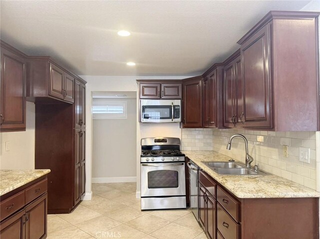 kitchen with appliances with stainless steel finishes, sink, backsplash, light stone counters, and light tile patterned floors