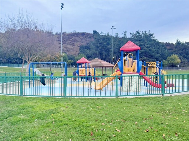 view of playground featuring a mountain view, a pool, and a yard