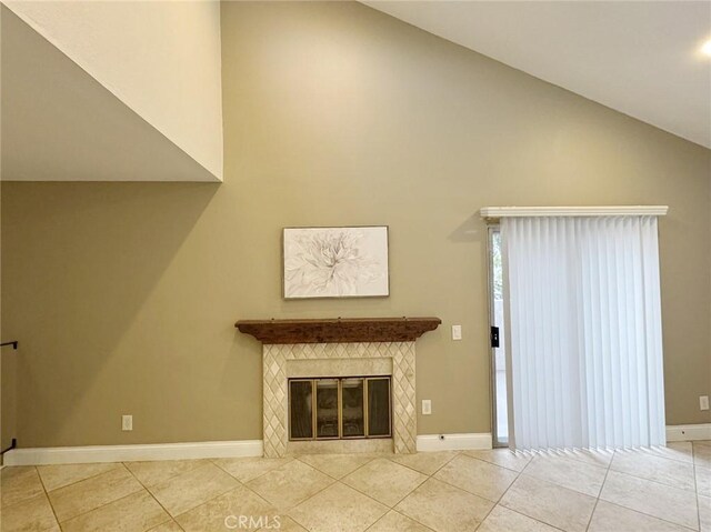 unfurnished living room featuring vaulted ceiling, light tile patterned floors, and a tile fireplace