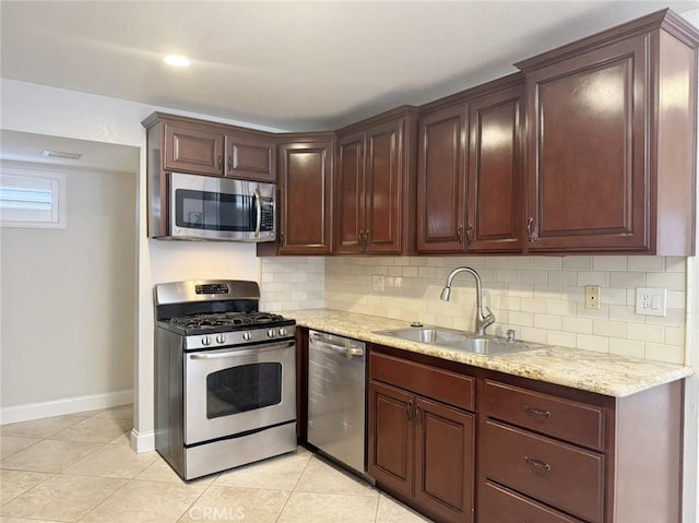 kitchen with light stone countertops, stainless steel appliances, tasteful backsplash, sink, and light tile patterned flooring