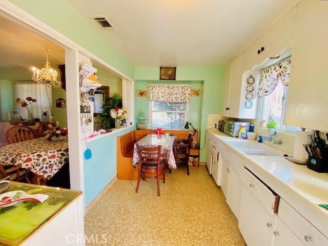 kitchen with hanging light fixtures, a chandelier, sink, and white cabinetry