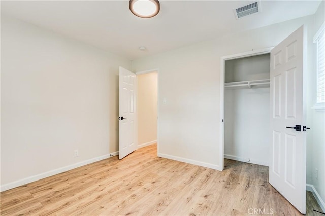 unfurnished bedroom with visible vents, baseboards, a closet, and wood finished floors