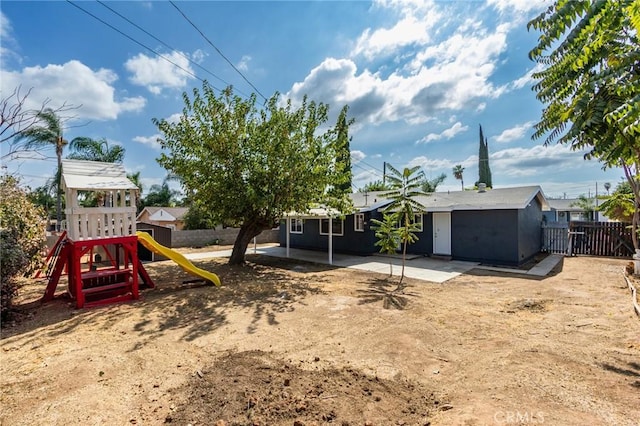 view of yard featuring a patio, a playground, and fence