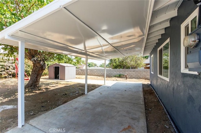 view of patio with an outdoor structure, fence, and a shed