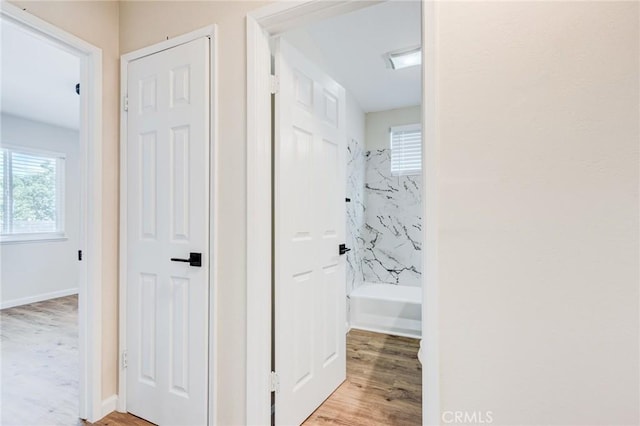 corridor featuring light wood finished floors and baseboards