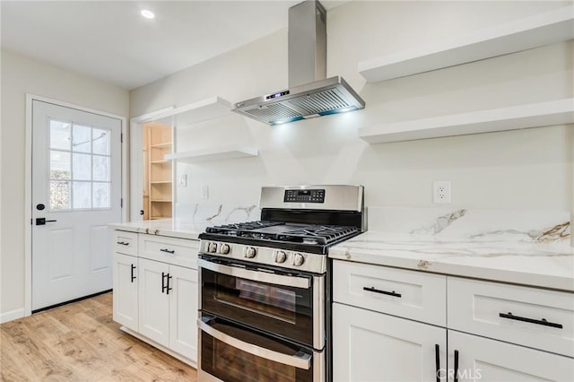 kitchen featuring open shelves, light stone counters, wall chimney exhaust hood, and double oven range