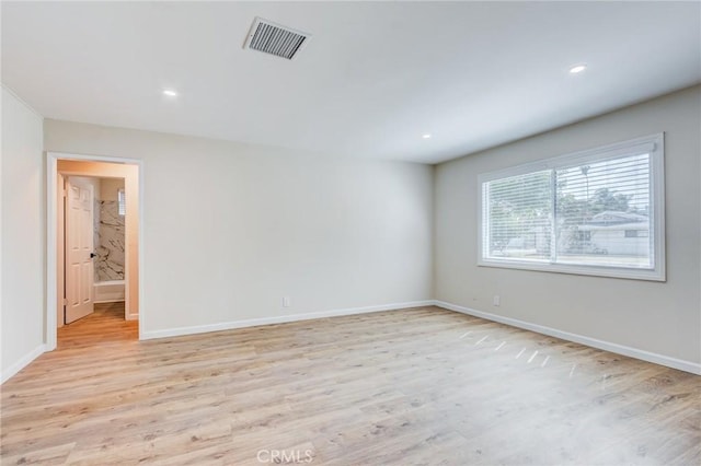 spare room featuring visible vents, light wood-style flooring, and baseboards