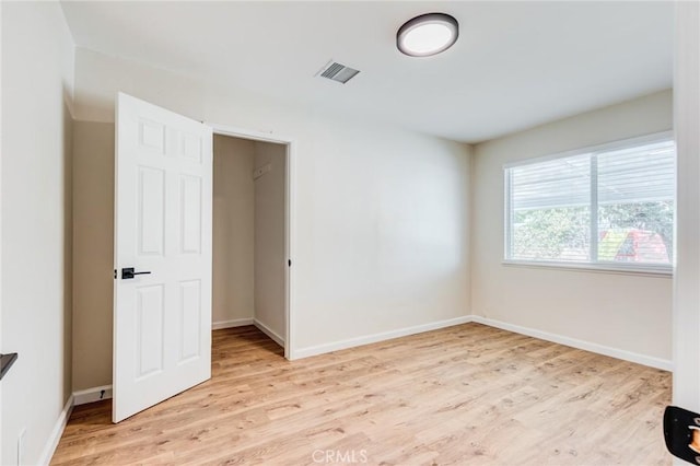 spare room featuring light wood-type flooring, visible vents, and baseboards