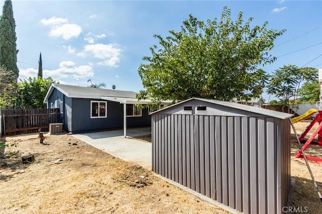 view of shed featuring central AC unit, a playground, and fence