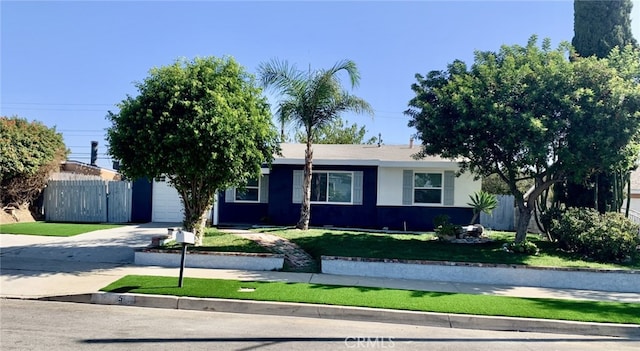 ranch-style home with a front lawn, fence, stucco siding, a garage, and driveway