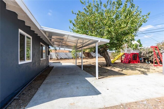 exterior space with fence, a carport, and a playground