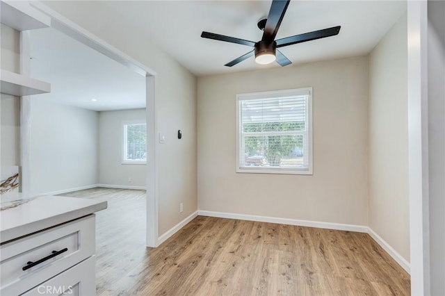 unfurnished dining area featuring baseboards, light wood-style floors, and ceiling fan