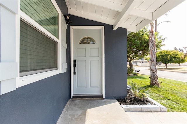 doorway to property featuring stucco siding and a porch