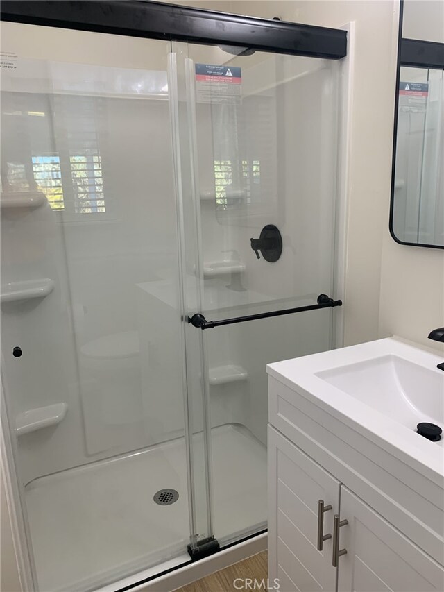 bathroom featuring vanity, hardwood / wood-style flooring, and a shower with shower door