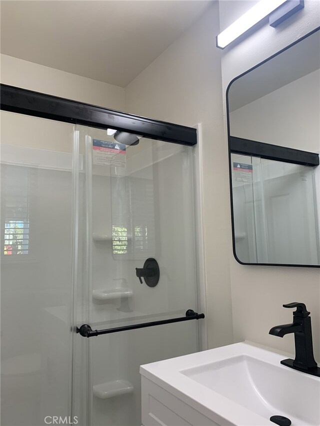 bathroom featuring a shower with door and vanity