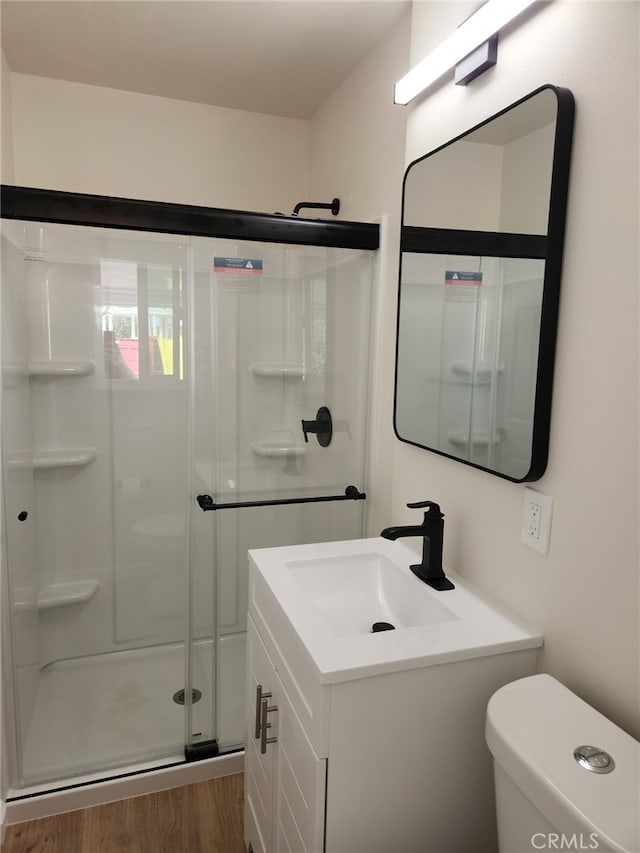 full bath featuring a shower stall, vanity, toilet, and wood finished floors