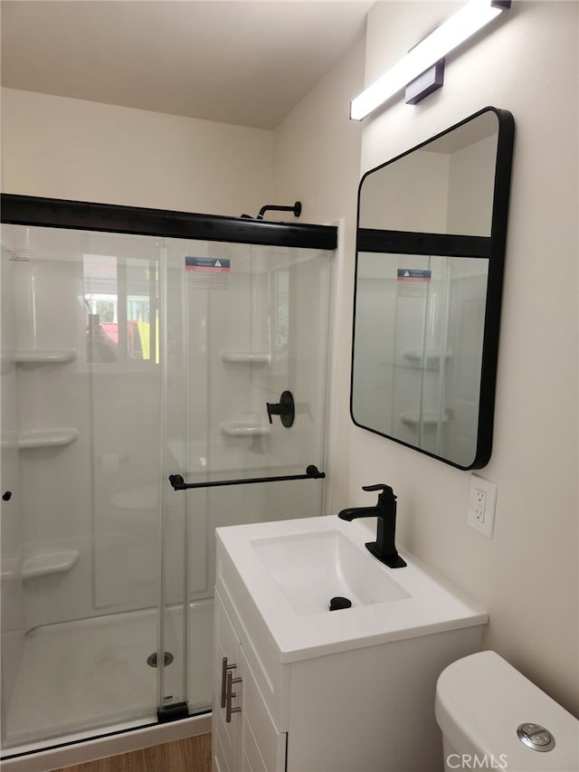 full bathroom featuring a shower stall, toilet, vanity, and wood finished floors