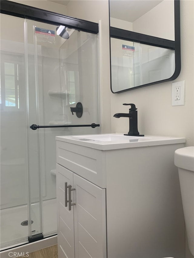 full bath featuring vanity, toilet, wood finished floors, and a shower stall