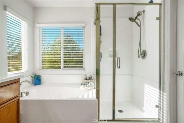 bathroom featuring independent shower and bath, a healthy amount of sunlight, and vanity