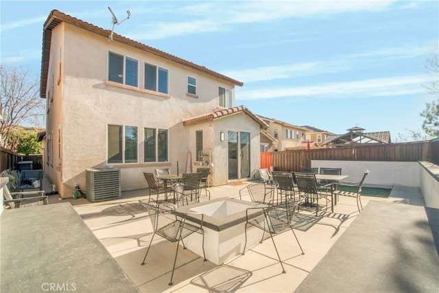 rear view of property with central AC unit, a patio area, and an outdoor fire pit