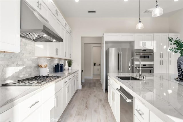 kitchen with range hood, white cabinetry, stainless steel appliances, and sink