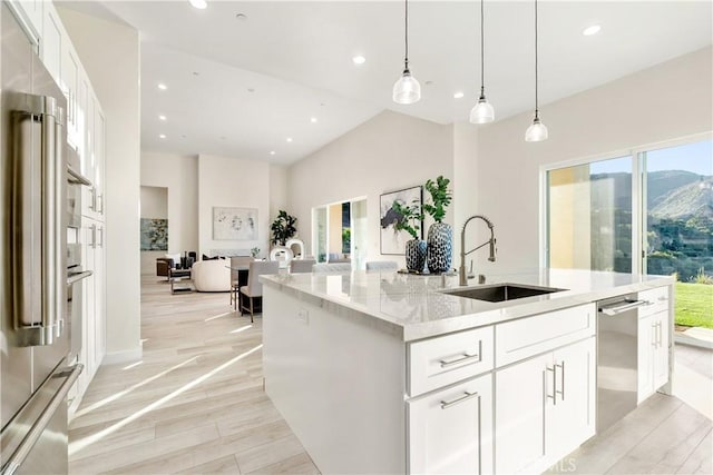 kitchen with appliances with stainless steel finishes, white cabinets, light stone counters, and sink