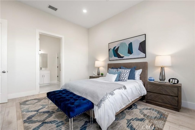 bedroom featuring ensuite bathroom and light hardwood / wood-style flooring