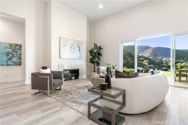 living room featuring a towering ceiling, a fireplace, a mountain view, and light hardwood / wood-style flooring