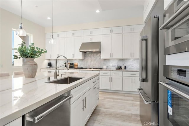 kitchen featuring appliances with stainless steel finishes, pendant lighting, white cabinets, and sink