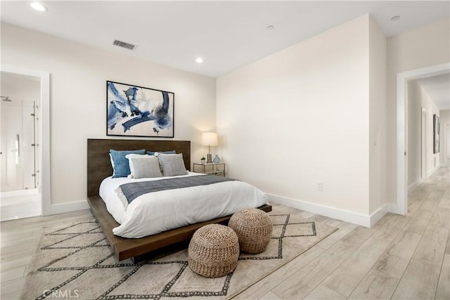 bedroom featuring ensuite bath and light wood-type flooring