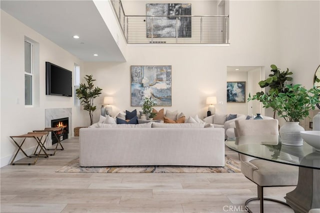 living room with a high ceiling, a fireplace, and light hardwood / wood-style flooring