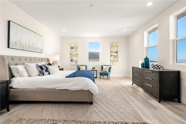 bedroom with light hardwood / wood-style floors and multiple windows