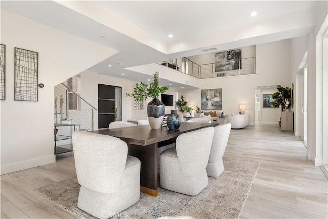 dining space featuring a high ceiling and light wood-type flooring