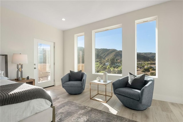 bedroom with light wood-type flooring, access to exterior, a mountain view, and multiple windows