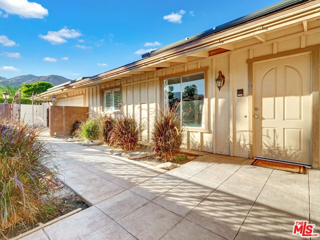 property entrance with a garage, a mountain view, and a patio