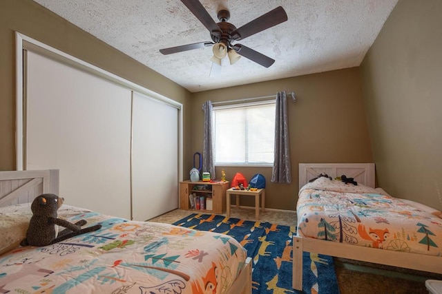 carpeted bedroom with ceiling fan, a textured ceiling, and a closet