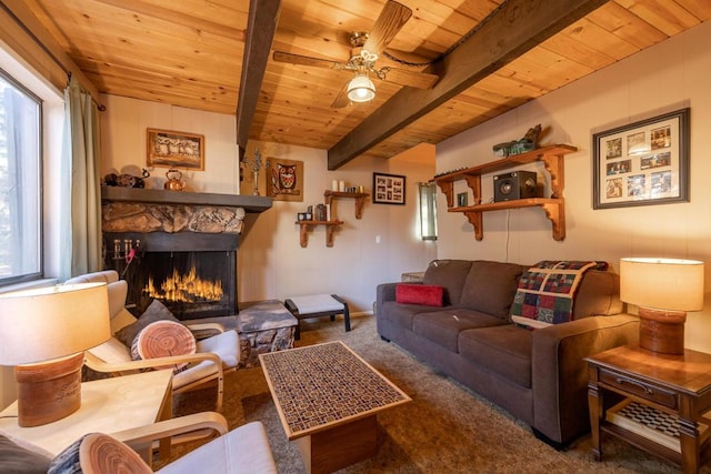 living room with wood ceiling, a stone fireplace, carpet flooring, ceiling fan, and beam ceiling