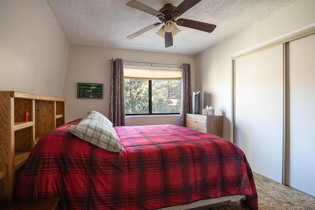 bedroom with a textured ceiling, ceiling fan, a closet, and carpet floors