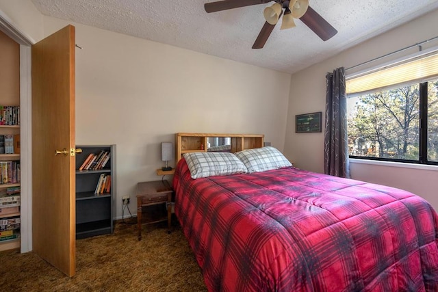 bedroom featuring ceiling fan, a textured ceiling, and dark colored carpet