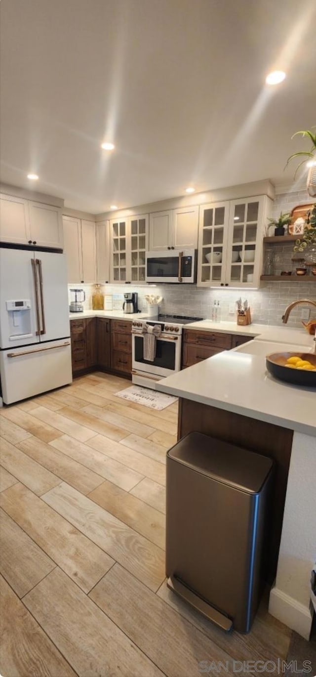 kitchen with white appliances, white cabinets, light hardwood / wood-style flooring, and kitchen peninsula