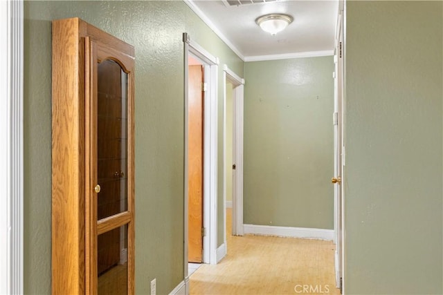 corridor with ornamental molding and light hardwood / wood-style flooring