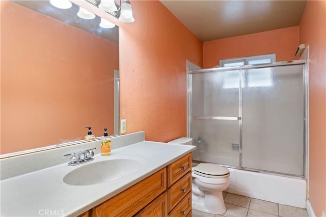 full bathroom featuring bath / shower combo with glass door, tile patterned floors, vanity, and toilet