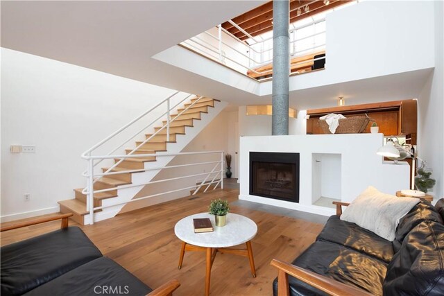 living room with hardwood / wood-style flooring, a high ceiling, and a fireplace