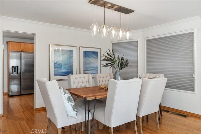 dining area with crown molding and light hardwood / wood-style flooring